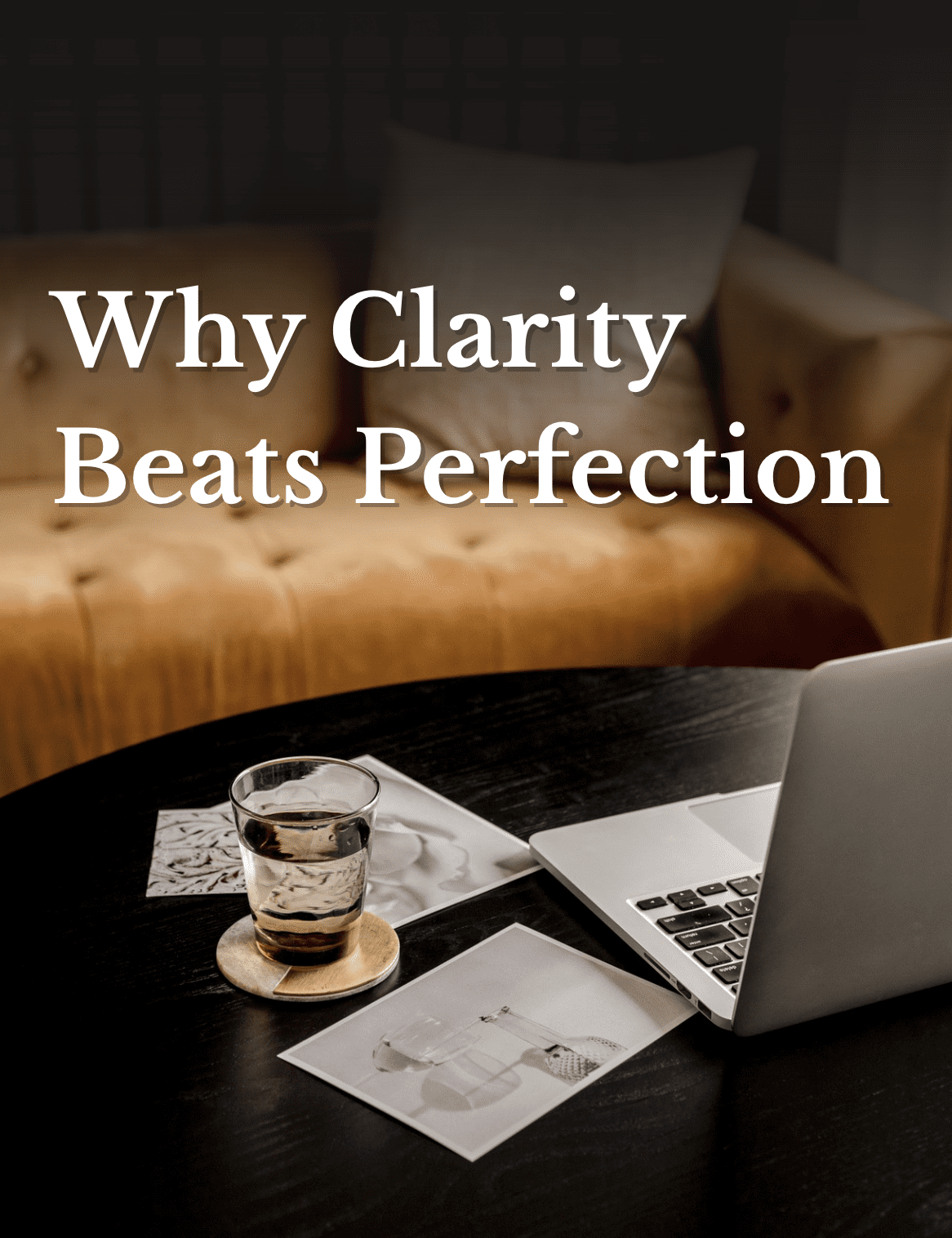Open laptop and glass of water on a coffee table with the text overlay: “Why Clarity Beats Perfection: 3 Ways to Stop Stalling and Start Building.